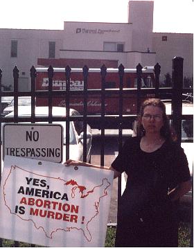 Terri stands solemnly outside Planned Parenthood's death chamber as the armoured car hauls away the blood money